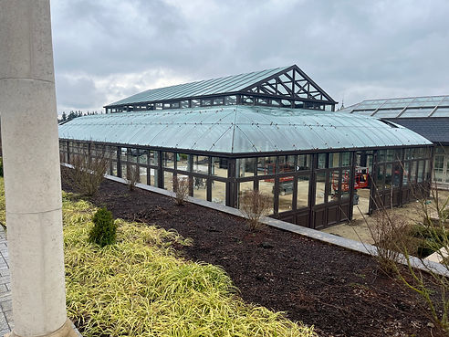 Exterior view of the Arboretum's glass and metal structure, seen past a stone column