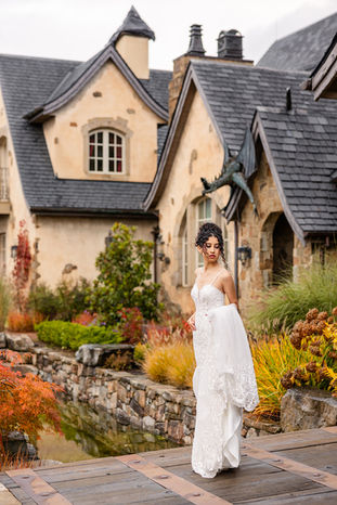 Bride walking past the chateau's turret and stone facade at dusk