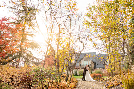 Bride and groom walking a golden autumn path toward the chateau at sunset