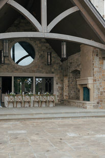 Vaulted stone dining pavilion set with long wooden tables and a fireplace