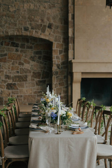 Indoor-outdoor dining space with blue and yellow florals set before a carved stone fireplace