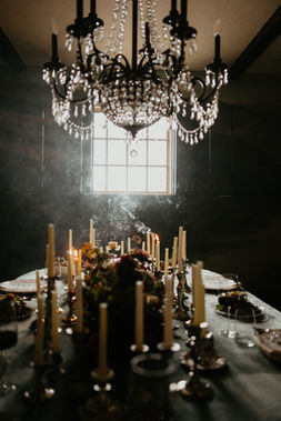 Candlelit dinner table glowing softly beneath a crystal chandelier