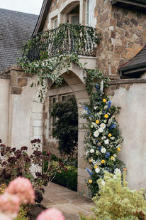 Ivy-draped archway leading into a courtyard, decorated with blue and yellow florals