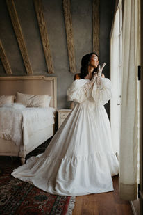 Bride in a sleeved gown pausing thoughtfully in a rustic beamed attic room