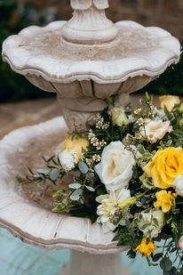 Stone fountain basin filled with a yellow and white floral arrangement