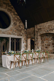 Long reception table set beneath a soaring stone gable and dark timber trusses