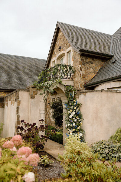 Chateau exterior with a hydrangea garden and a floral garland draping the balcony