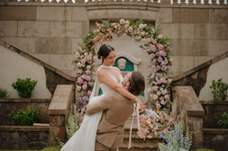 Bride and groom embracing beneath a floral arch on the chateau's stone steps