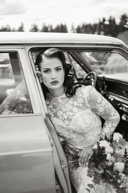 Bride in a vintage lace gown leaning from a classic car window